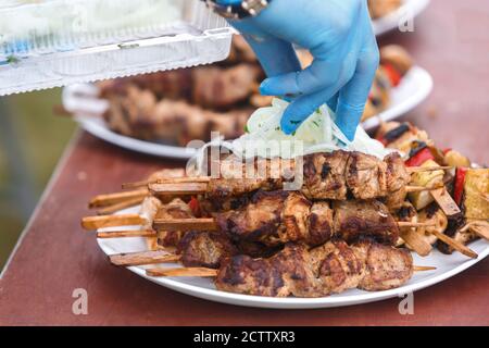 Der Schischkebab auf den hölzernen Spieß liegt auf dem Teller bestreut Mit Zwiebeln Stockfoto