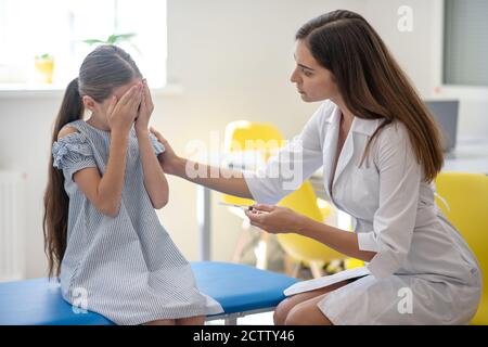 Mädchen, die auf die Spritze in Ärzte Hand und Gefühl Erschrocken Stockfoto