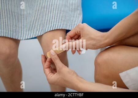 Nahaufnahme Bild der Ärzte Hände Anwendung Putz auf die Knie Stockfoto