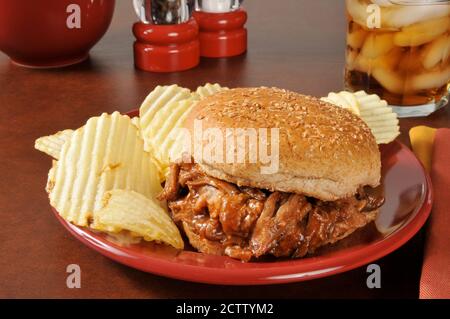 Ein Pulled Schweinefleisch, oder Grill Rindfleisch Sandwich auf einem Brötchen mit Kartoffelchips Stockfoto