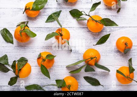 Frische orange Mandarinen, Mandarine mit grünen Blättern auf weißem Holzgrund. Draufsicht Stockfoto