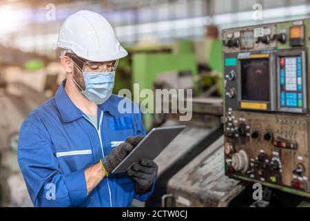 Arbeiter trägt Gesichtsschutz oder Einweg-Gesichtsmaske während der Arbeit Service in der Fabrik, um Coronavirus (Covid-19) oder Luftverschmutzung zu verhindern Im Werk Stockfoto