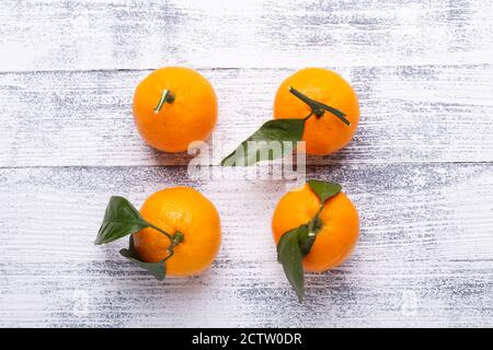 Frische orange Mandarinen, Mandarine mit grünen Blättern auf weißem Holzgrund. Draufsicht Stockfoto