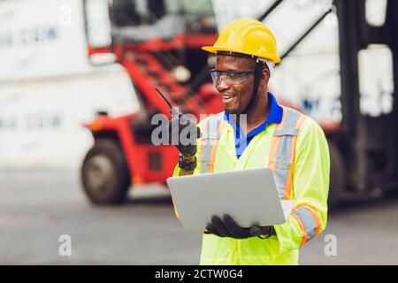 Afroamerikanische schwarze Arbeiter arbeiten in logistischen Versand Fracht Hafen vor Ort glückliche Arbeit Kontrolle Laden mit Radio und Laptop. Stockfoto