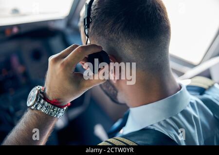 Selbstbewusster Mann trägt Uniform sitzt in der Kabine des Flugzeugs Stockfoto