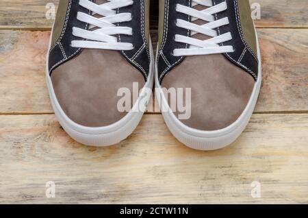 Neue Mode grau-grüne Herren Sneaker mit weißen Sohlen und weißen Schnürsenkeln auf einem Holzhintergrund Nahaufnahme. Socke Teil der Herren Sneakers, oben ansehen Stockfoto