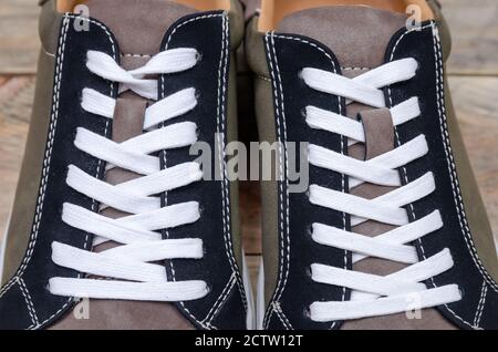 Neue Mode grau-grüne Herren Sneaker mit weißen Sohlen und weißen Schnürsenkeln auf einem Holzhintergrund Nahaufnahme. Socken sind Teil der Herren Sneakers Stockfoto