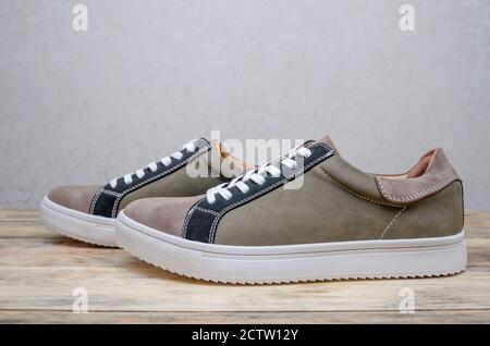 Neue Mode grau-grüne Herren Sneaker mit weißen Sohlen und weiß Schnürsenkel auf einem Holzhintergrund Nahaufnahme Stockfoto