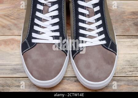 Neue Mode grau-grüne Herren Sneaker mit weißen Sohlen und weißen Schnürsenkeln auf einem Holzhintergrund Nahaufnahme. Socke Teil der Herren Sneakers, oben ansehen Stockfoto