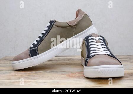 Neue Mode grau-grüne Herren Sneaker mit weißen Sohlen und weiß Schnürsenkel auf einem Holzhintergrund Nahaufnahme Stockfoto