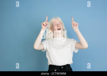 Zeigen, auswählen. Nahaufnahme Porträt der schönen kaukasischen Albino Mädchen auf blau. Blonde weibliche Modell mit stilvollen Look. Konzept des Gesichtsausdrucks, menschliche Emotionen, Kindheit, Werbung, Verkauf, Vielfalt. Stockfoto