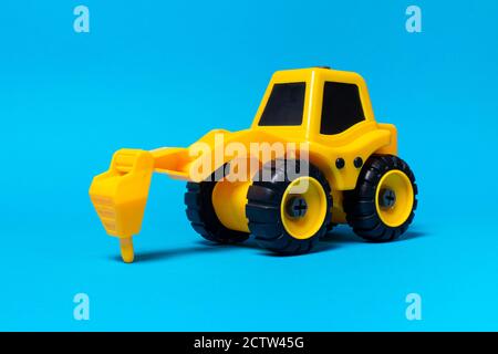Kinder Spielzeug gelben Traktor LKW-Bohrer auf einem blauen Hintergrund. Baumaschinen aus Kunststoff, Spielzeugladen Stockfoto