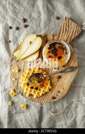 Kandierte Fruchtgelee. Birnenmarmelade mit Kaffeebohnen. Glas Birnenmarmelade auf Holz Schneidebrett auf Leinenhintergrund Stockfoto