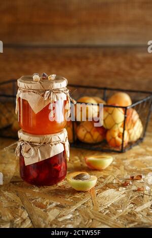 Aprikosenmarmelade auf einem rustikalen Holzhintergrund. Zwei Gläser Obst hausgemachte Marmelade. Glasgefäße mit verschiedenen Arten von Marmelade und Obst. Stockfoto