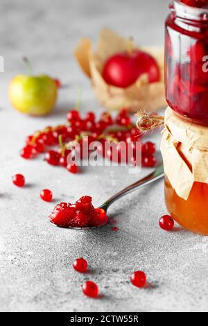 Löffel köstliche Fruchtkonfitüre. Zwei Gläser Obst hausgemachte Marmelade. Glasgefäße mit verschiedenen Arten von Marmelade und Beeren. Pflaume und rote Johannisbeere konfitüren Stockfoto