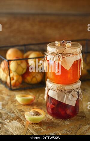 Aprikosenmarmelade auf einem rustikalen Holzhintergrund. Zwei Gläser Obst hausgemachte Marmelade. Glasgefäße mit verschiedenen Arten von Marmelade und Obst. Stockfoto