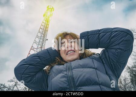 Die Frau ist ihr Kopf in der Nähe der BTS-Holding. Schädliche Strahlung von Mobilfunk 5G-Netzwerk sender Konzept Stockfoto