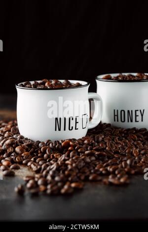 Schwarze Kaffeebohnen Studioaufnahme. Frisch geröstete Kaffeebohnen im Glas. Kaffee in weißen Tassen Stockfoto