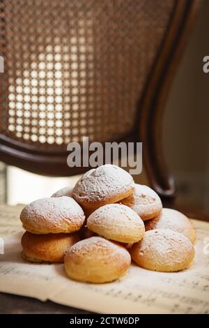 Hausgemachte Profiterolen auf dem Notenblatt mit Noten. Profiteroles (choux à la crème) - Französische Choux Gebäck Kugeln gefüllt mit Pudding oder Quark Stockfoto