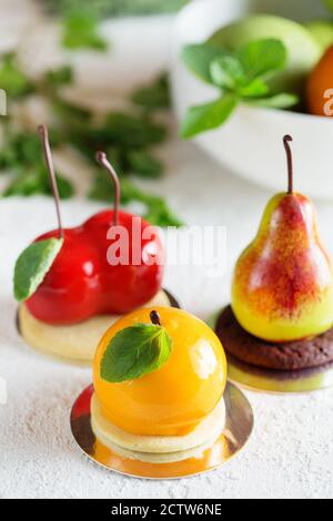 Mousse Dessert in Form einer Birnenfrucht, Orangenfrucht und Kirsche. Mousse Cake Stockfoto