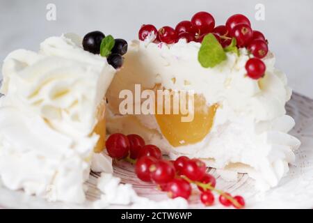 Pavlova Kuchen in einem Schnitt mit Sahne und frischen Sommerbeeren. Nahaufnahme von Pavlova Dessert mit Waldfrüchten und Minze. Food-Fotografie Stockfoto