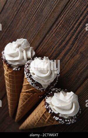 Eiszapfen auf Holztisch. Weiches Eis oder gefrorene Cremes in Zapfen. Eiscreme mit Waffel-Marshmallow Stockfoto