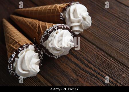 Eiszapfen auf Holztisch. Weiches Eis oder gefrorene Cremes in Zapfen. Eiscreme mit Waffel-Marshmallow Stockfoto