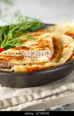 Heiße hausgemachte Pasties auf einem schwarzen Gericht mit Tomaten serviert Und Dill Stockfoto