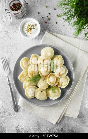 Die Fleischknödel - die russischen Pelmeni, die Ravioli mit dem Fleisch auf dem grauen Teller. Flache Lay-Komposition. Food-Fotografie Stockfoto