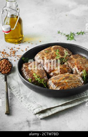 Köstliche gegrillte Leberfleischbällchen mit Buchweizen in einer natürlichen Hülle. Leberpasteten auf der kleinen Bratpfanne mit Thymian serviert. Food-Fotografie. Stockfoto