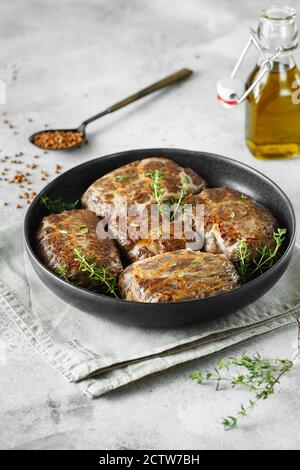 Köstliche gegrillte Leberfleischbällchen mit Buchweizen in einer natürlichen Hülle. Leberpasteten auf der kleinen Bratpfanne mit Thymian serviert. Food-Fotografie. Stockfoto