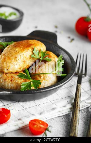Köstliche gegrillte Fleischbällchen vom Rind oder Huhn. Fleisch- oder Fischpasteten auf der kleinen Bratpfanne mit Petersilie und Tomaten serviert. Food-Fotografie. Stockfoto