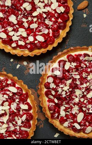 Schöne frisch gefertigte Kirschtarte mit Mandelchips dekoriert. Atemberaubende Kirschkuchen flach Lay Zusammensetzung. Food-Fotografie. Prozess der Herstellung von Tart. Stockfoto