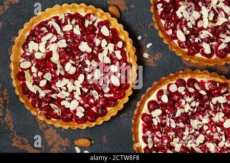Schöne frisch gefertigte Kirschtarte mit Mandelchips dekoriert. Atemberaubende Kirschkuchen flach Lay Zusammensetzung. Food-Fotografie. Prozess der Herstellung von Tart. Stockfoto