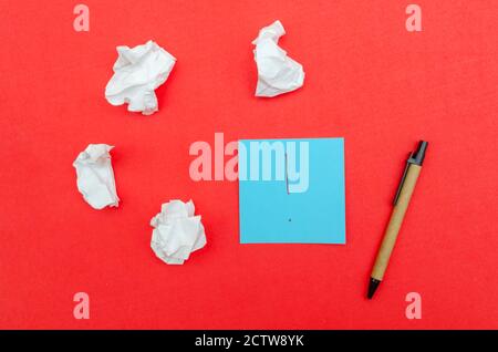 Blaues Blatt Papier mit Ausrufezeichen, zerknittertes Papier und Stift auf rotem Hintergrund, Draufsicht. Stockfoto