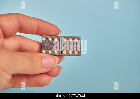 Eine Frauenhand hält einen schwarzen Domino Chip. Nahaufnahme Stockfoto