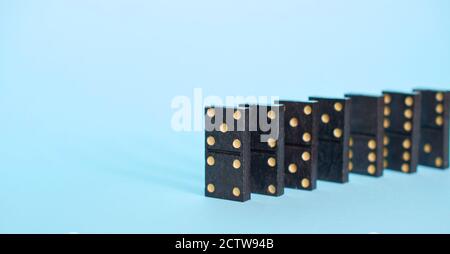 Dominoes Brettspiel-Chips in einer Reihe auf einem soliden blauen Hintergrund Nahaufnahme angezeigt. Stockfoto