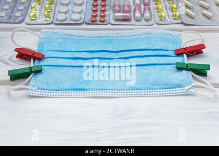 Medizinische Flatlay mit Maske und Tabletten auf weißem Holzhintergrund. Medizinisches Konzept. Draufsicht. Stockfoto