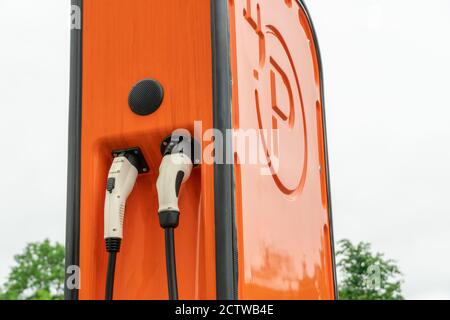 Orangefarbene Ladestation für Elektrofahrzeuge vor einem grau-weißen Himmel Nahaufnahme Stockfoto