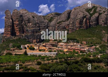 Los Mallos de Agüero (die Mallets oder Ninepins von Agüero), auch bekannt als die Syncline Hills, ragen dramatisch über dem kleinen Dorf der Pyrenäen in der Provinz Huesca, Aragon, Spanien. Agüero wird von der spektakulären Konglomeratgesteinsformation des Zuckerhuts aus der Tertiärzeit, die über viele Millionen von Jahren zu massiven rötlichen Säulen erodiert wurde, heimgesucht. Stockfoto