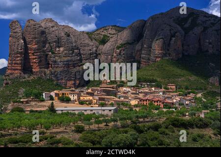 Los Mallos de Agüero (die Mallets oder Ninepins von Agüero), auch bekannt als die Syncline Hills, ragen dramatisch über dem kleinen Dorf der Pyrenäen in der Provinz Huesca, Aragon, Spanien. Agüero wird von der spektakulären Konglomeratgesteinsformation des Zuckerhuts aus der Tertiärzeit, die über viele Millionen von Jahren zu massiven rötlichen Säulen erodiert wurde, heimgesucht. Stockfoto