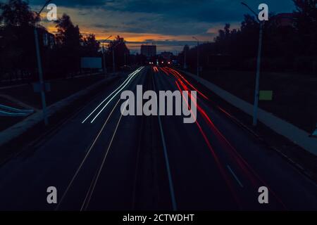 Lange Exposition des Verkehrs auf der Straße in der Stadt bei Sonnenuntergang. Stockfoto