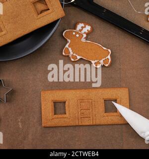 Junge Frau ist Dekoration Weihnachten Lebkuchen Haus Cookies Keks zu Hause mit Zuckerguss Belag in Sack, Nahaufnahme, Lifestyle. Stockfoto