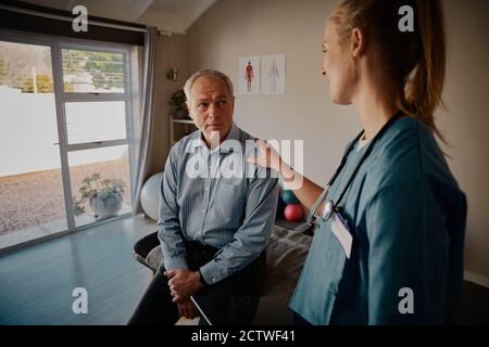 Junge weiße Krankenschwester tröstet ältere männliche Patienten im Krankenhaus Stockfoto