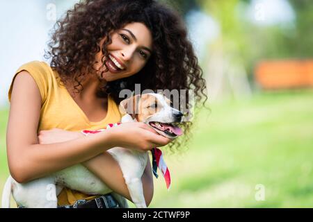 Lachende Frau, die die Kamera anschaut, während sie Jack russell Terrier streichelt Hund Stockfoto