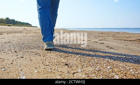 Nahaufnahme eines Männerfußes, der am Meer entlang läuft Der Strand Stockfoto