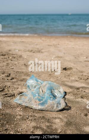 Plastiktüte links an einem Sandstrand. Stockfoto