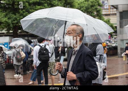 Tokio, Japan. September 2020. Ein älterer Mann, der einen Regenschirm hält, wartet an einem regnerischen Tag in Tokio auf ein grünes Licht am Shibuya Crossing. Kredit: SOPA Images Limited/Alamy Live Nachrichten Stockfoto