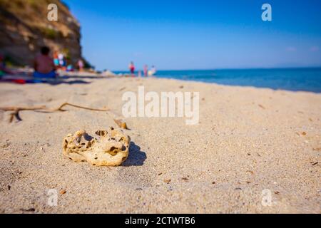 Hohle Felsen ist auf dem Sandstrand mit Meer in der Ferne platziert. Stockfoto