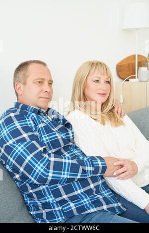 Taille Porträt des reifen Paares in häuslichen Interieur auf Sofa. Schöner Mann und Frau mittleren Alters Stockfoto